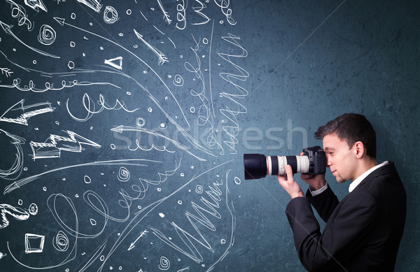 Photographer boy shooting images while energetic hand drawn lines and doodles come out of the camera Stock photo © ra2studio