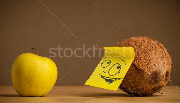 Coconut with post-it note looking curiously at apple Stock photo © ra2studio