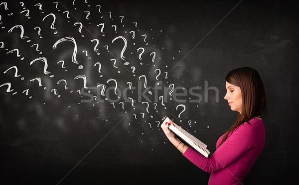 Stock photo: Pretty woman reading a book with question marks coming out from 