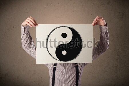 Stock photo: Businessman holding a paper with a yin-yang on it in front of hi