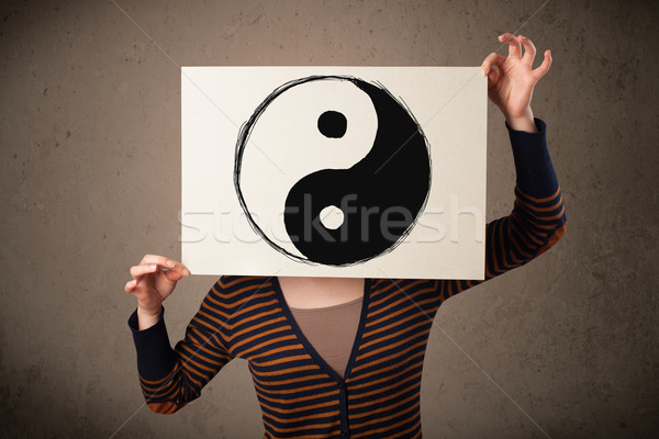 Woman holding a paper with a yin-yang on it in front of her head Stock photo © ra2studio