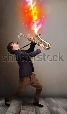 Young man playing on saxophone with colorful sound waves Stock photo © ra2studio