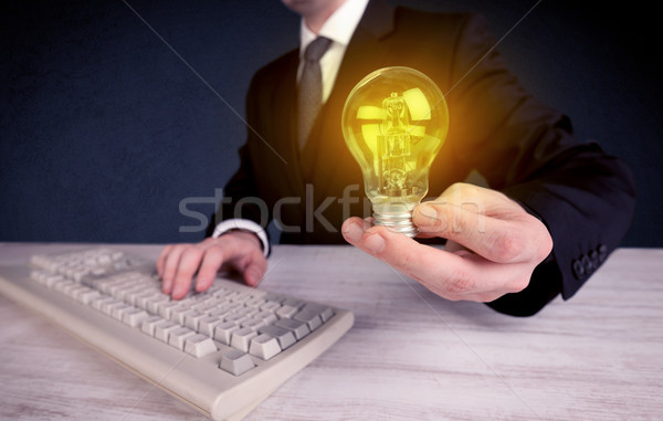 man in suit holding a glowing yellow light bulb Stock photo © ra2studio