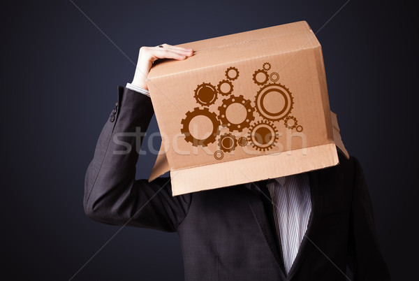 Young man gesturing with a cardboard box on his head with spur w Stock photo © ra2studio