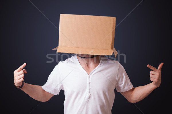 Young man gesturing with a cardboard box on his head Stock photo © ra2studio