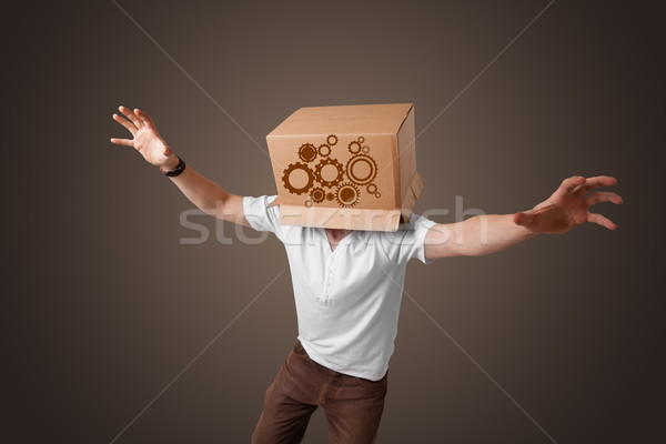 Young man gesturing with a cardboard box on his head with spur w Stock photo © ra2studio
