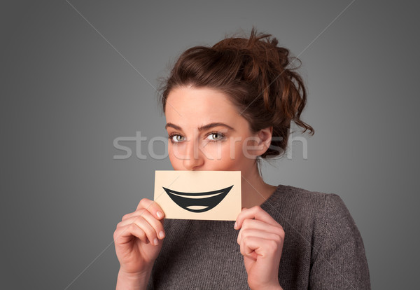 Happy pretty woman holding card with funny smiley Stock photo © ra2studio