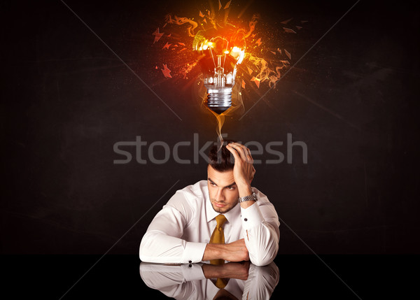 Businessman sitting under a blowing idea bulb Stock photo © ra2studio