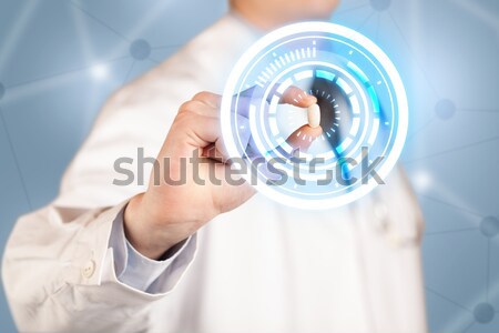 Male doctor holding a pill with glowing circles Stock photo © ra2studio