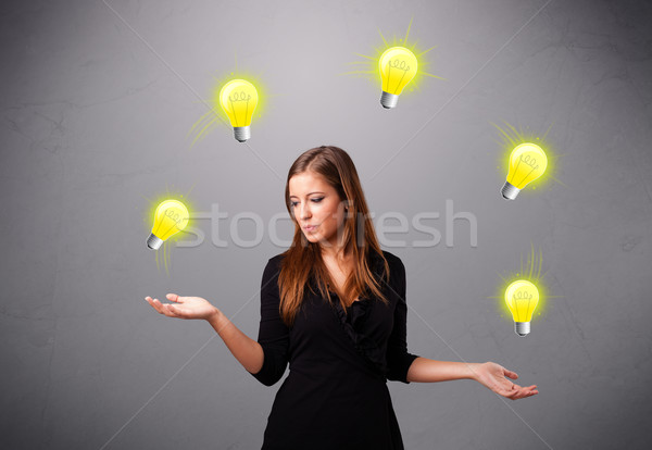 Stock photo: young lady standing and juggling with light bulbs