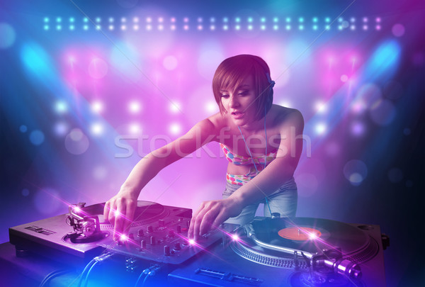 Stock photo: Disc jockey mixing music on turntables on stage with lights and 