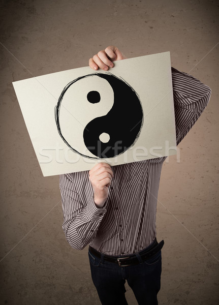 Businessman holding a paper with a yin-yang on it in front of hi Stock photo © ra2studio