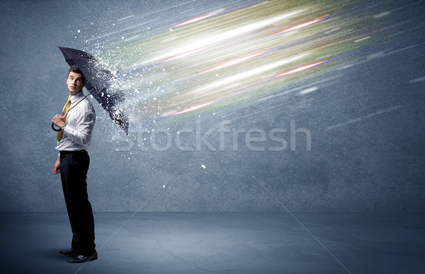 Business man defending light beams with umbrella concept Stock photo © ra2studio