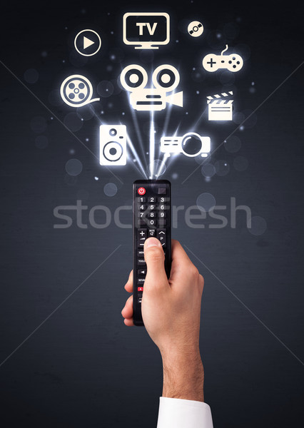 Hand with remote control and media icons Stock photo © ra2studio