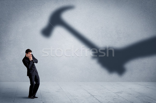 Business person afraid of a shadow hand holding hammer concept Stock photo © ra2studio