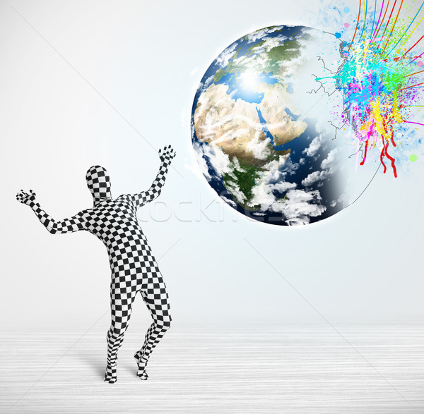 Stock photo: Funny man in body suit looking at colorful splatter earth