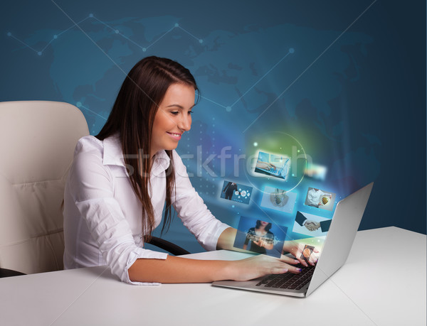 Beautiful girl sitting at desk and watching her photo gallery on Stock photo © ra2studio