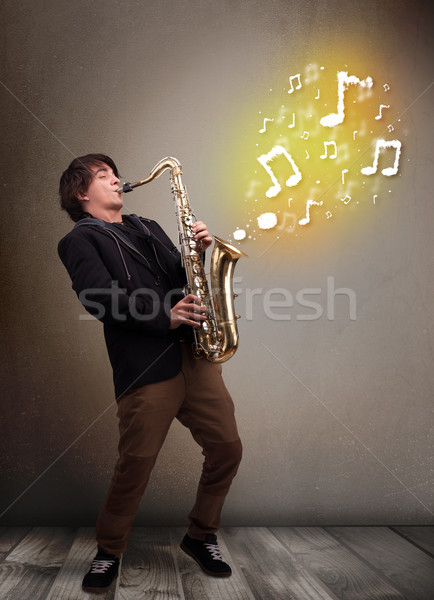 Guapo músico jugando saxófono notas musicales jóvenes Foto stock © ra2studio