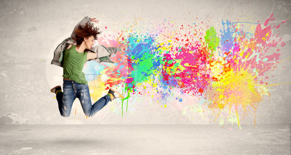 Happy teenager jumping with colorful ink splatter on urban backg Stock photo © ra2studio