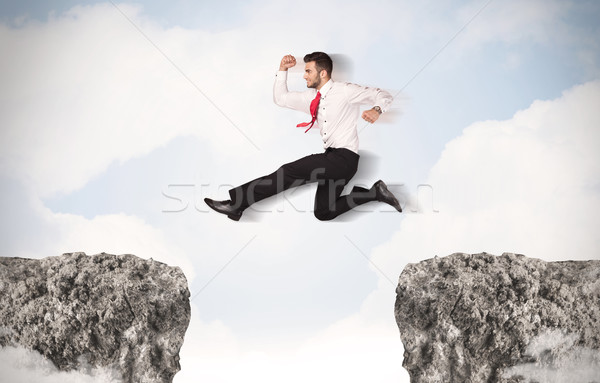 Stock photo: Funny business man jumping over rocks with gap