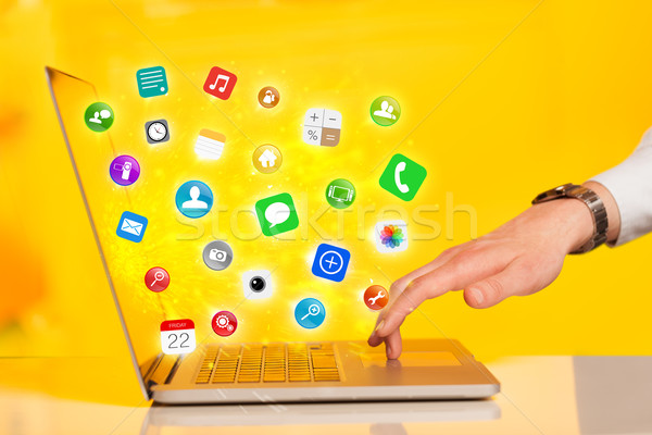 Hand pressing modern laptop with mobile app icons and symbols Stock photo © ra2studio