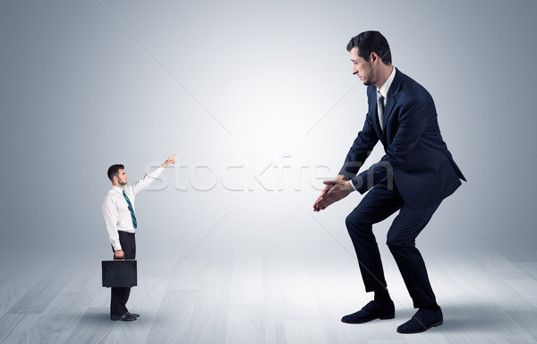 Small businessman pointing to a giant businessman Stock photo © ra2studio