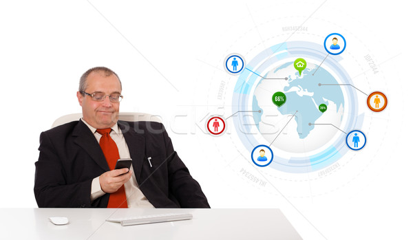 businessman sitting at desk and holding a mobilephone with globe and social icons, isolated on white Stock photo © ra2studio