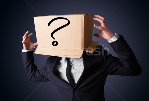 Stock photo: Businessman gesturing with a cardboard box on his head with ques