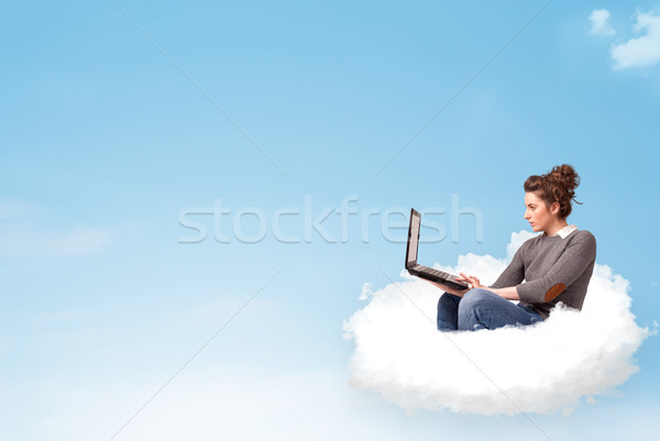 Stock photo: Young woman with laptop sitting on cloud with copy space