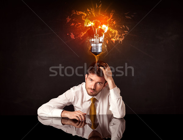 Businessman sitting under a blowing idea bulb Stock photo © ra2studio