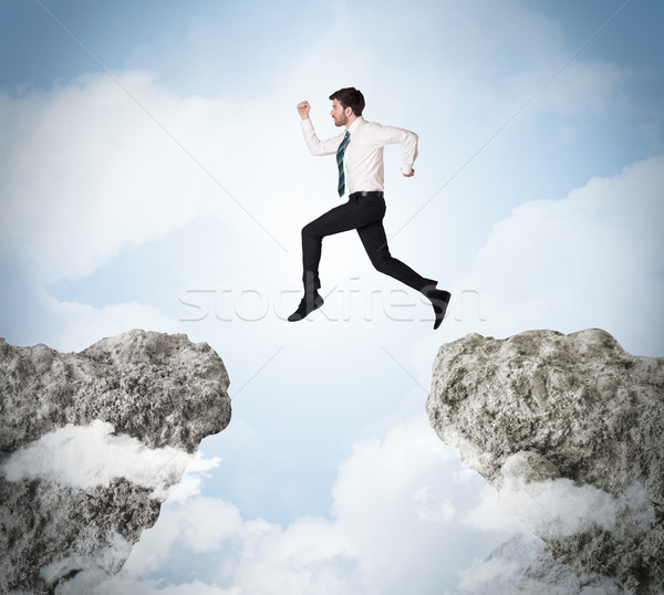 Stock photo: Happy business man jumping over a cliff 