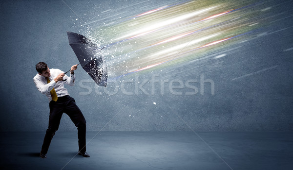 Business man defending light beams with umbrella concept Stock photo © ra2studio