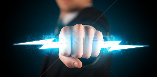 Stock photo: Business man holding glowing lightning bolt in his hands