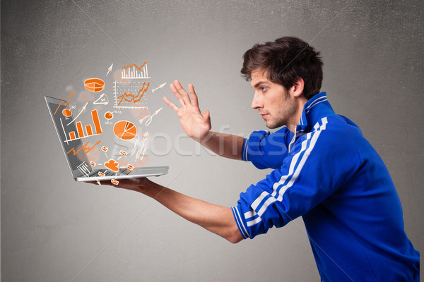 Stock photo: Handsome man holding laptop with graphs and statistics
