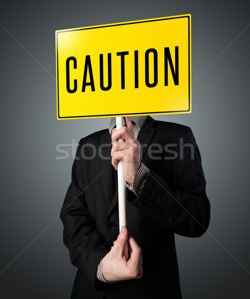 Businessman holding a caution sign Stock photo © ra2studio