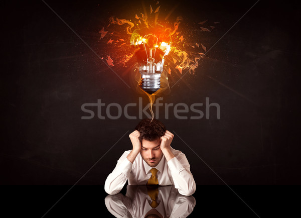 Businessman sitting under a blowing idea bulb Stock photo © ra2studio