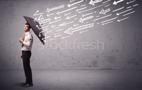 Business man standing with umbrella and drawn arrows hitting him Stock photo © ra2studio