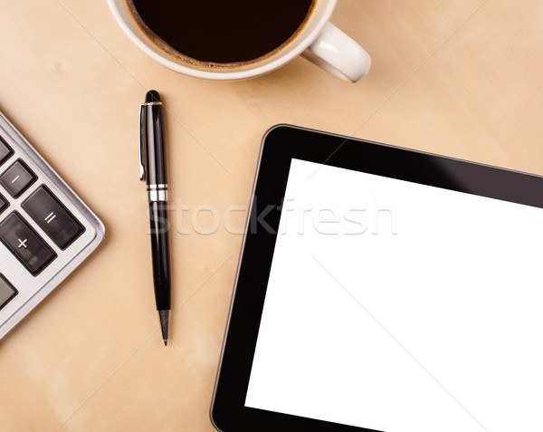 Stock photo: Tablet pc with empty space and a cup of coffee on a desk