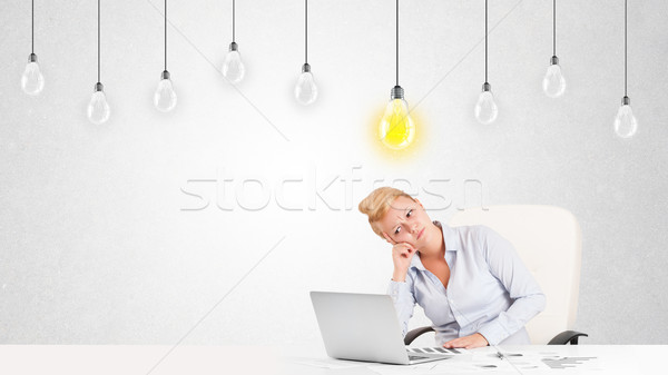 Business woman sitting at table with idea light bulbs Stock photo © ra2studio