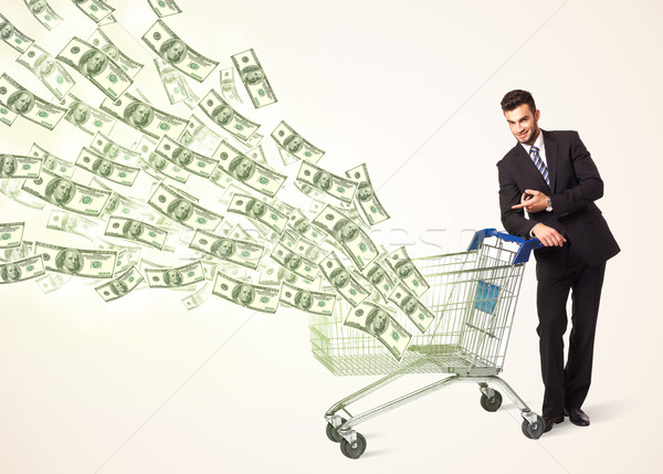 Businessman with shopping cart with dollar bills Stock photo © ra2studio