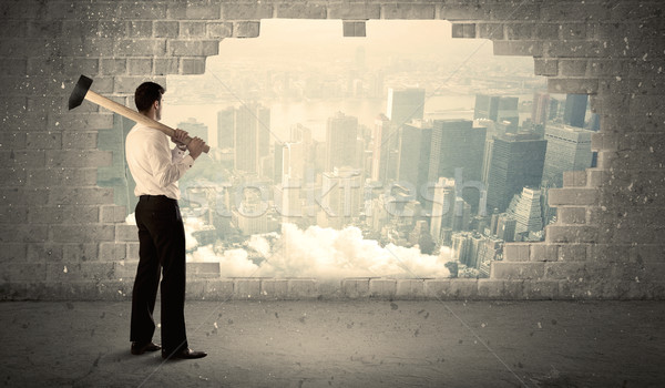 Stock photo: Business man hitting wall with hammer on city view