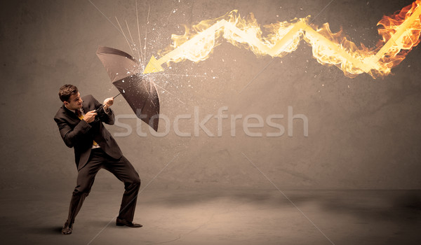 Business man defending himself from a fire arrow with an umbrell Stock photo © ra2studio