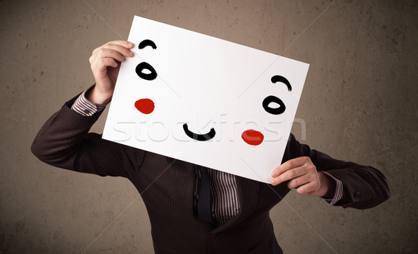 Stock photo: Businessman holding a cardboard with a smiley face on it