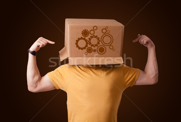 Young man gesturing with a cardboard box on his head with spur w Stock photo © ra2studio