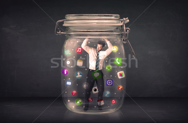 Businessman captured in a glass jar with colourful app icons con Stock photo © ra2studio