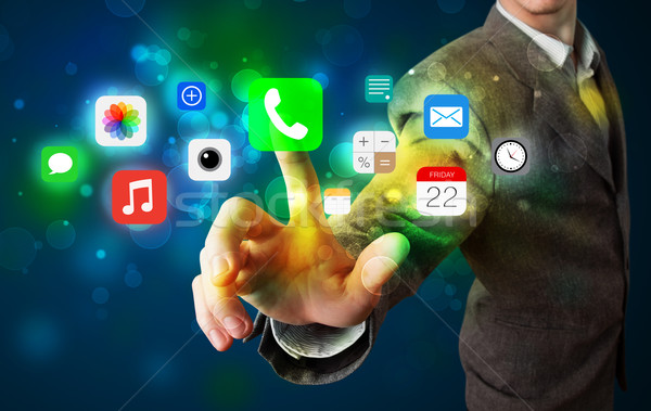 Handsome businessman pressing colorful mobile app icons with bok Stock photo © ra2studio