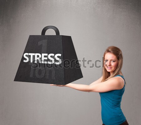 Young woman holding one ton of stress weight Stock photo © ra2studio