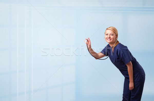 Pretty young nurse in hospital listening to empty copy space with sthetoscope Stock photo © ra2studio