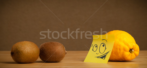 Lemon with post-it note looking curiously at kiwis Stock photo © ra2studio