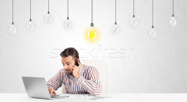 Business man sitting at table with idea light bulbs Stock photo © ra2studio